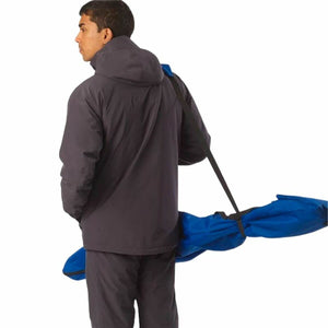 Man wearing a dark jacket carrying a blue ski rack, ideal for outdoor adventures and camping.
