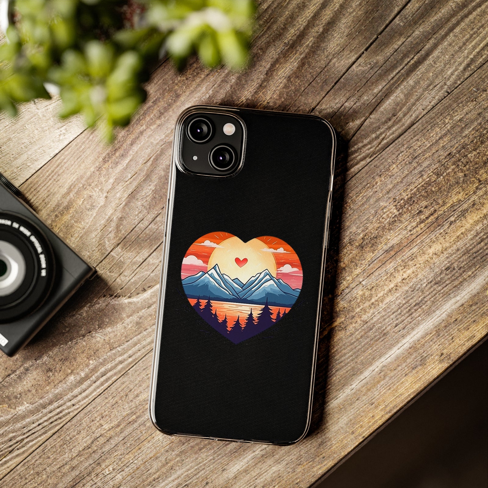 Phone case with mountain heart design on a wooden surface, ideal for outdoor lovers and adventure enthusiasts.