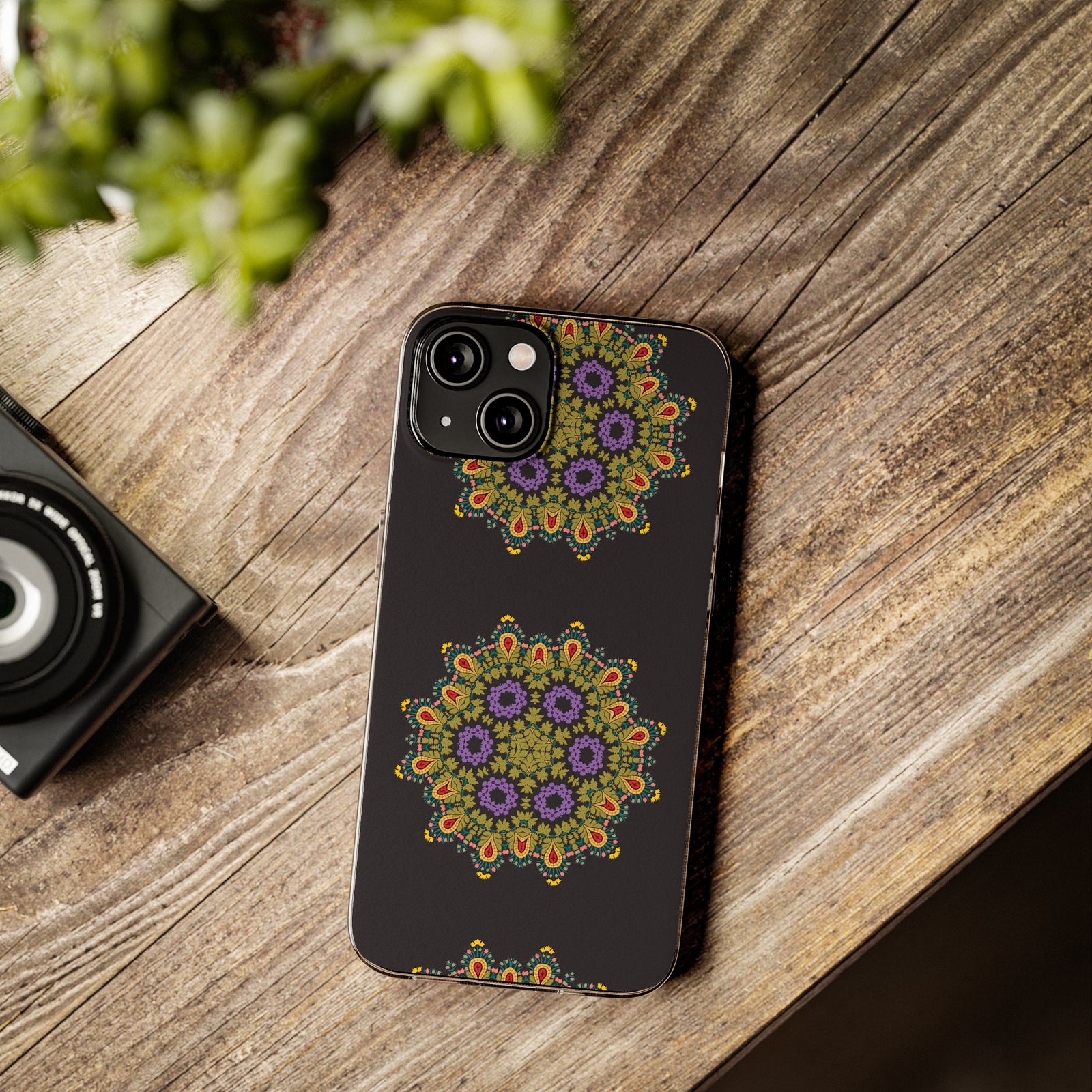 Gold Mandala phone case on a wooden table with camera and plant, showcasing custom design for outdoor adventures.