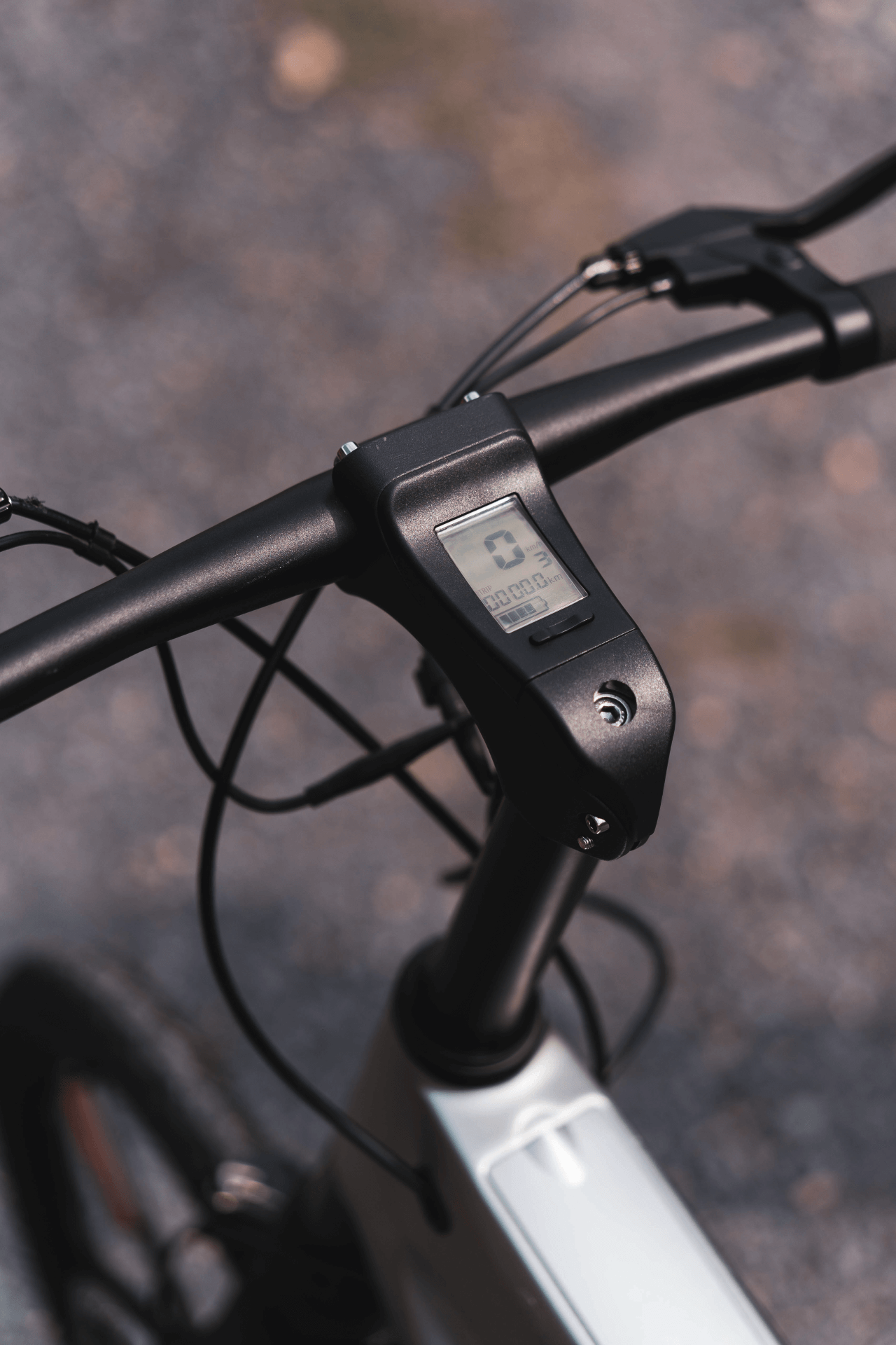 Digital LCD display on the handlebars of a carbon black e-bike, perfect for outdoor adventures and travel.