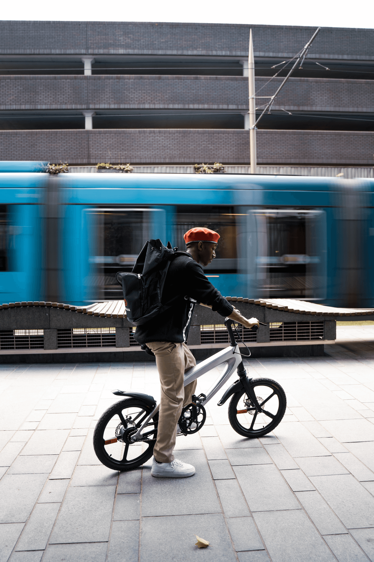 Person riding a sleek e-bike outdoors near a moving train, showcasing adventure and urban travel.