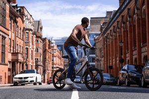 Person riding a Carbon Black E-Bike on an urban street, showcasing outdoor adventure and travel with style.