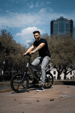 Young man riding an official carbon black e-bike in a city park, showcasing an outdoor adventure.