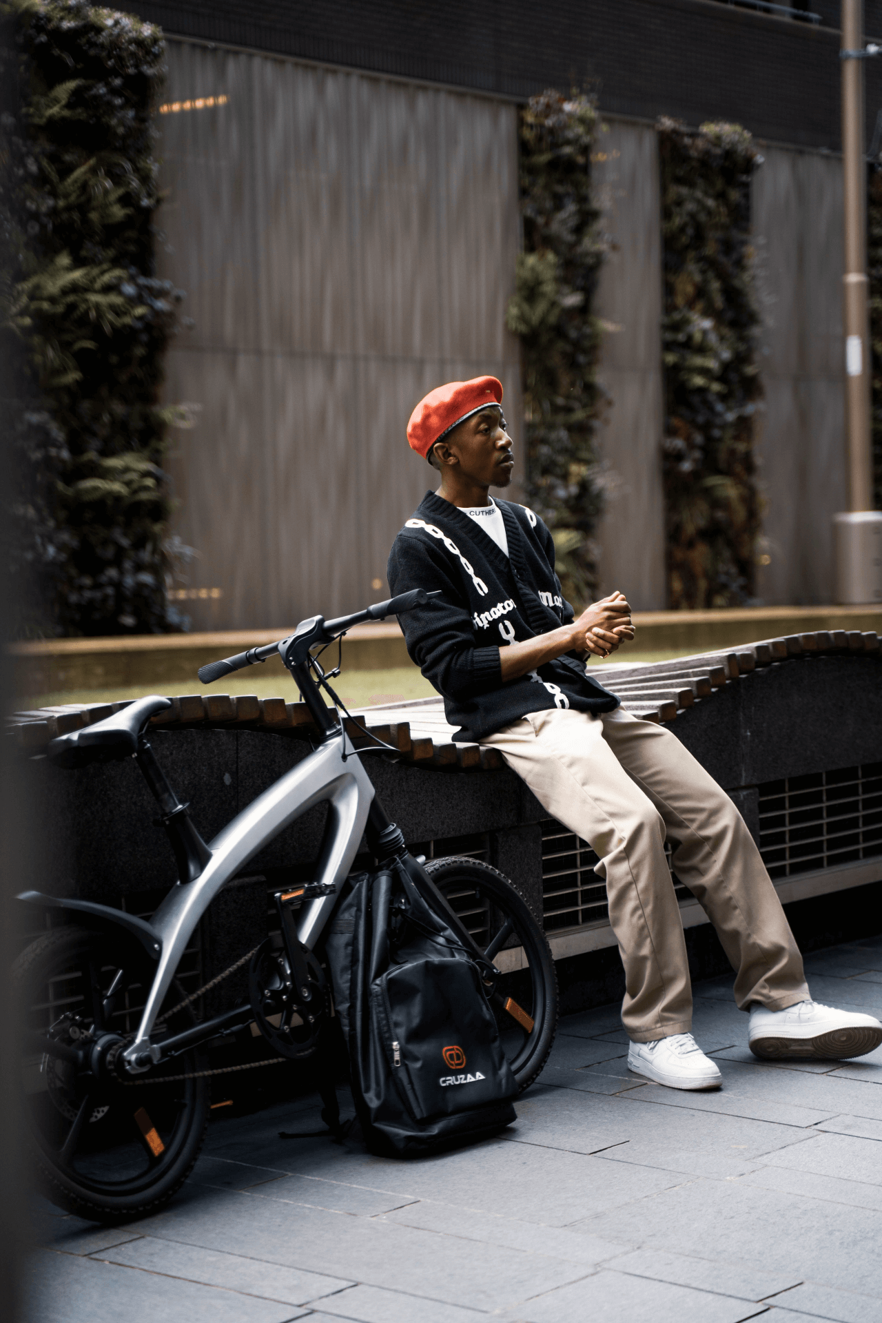 Stylish individual relaxing beside a sleek e-bike outdoors, showcasing urban adventure and sport.