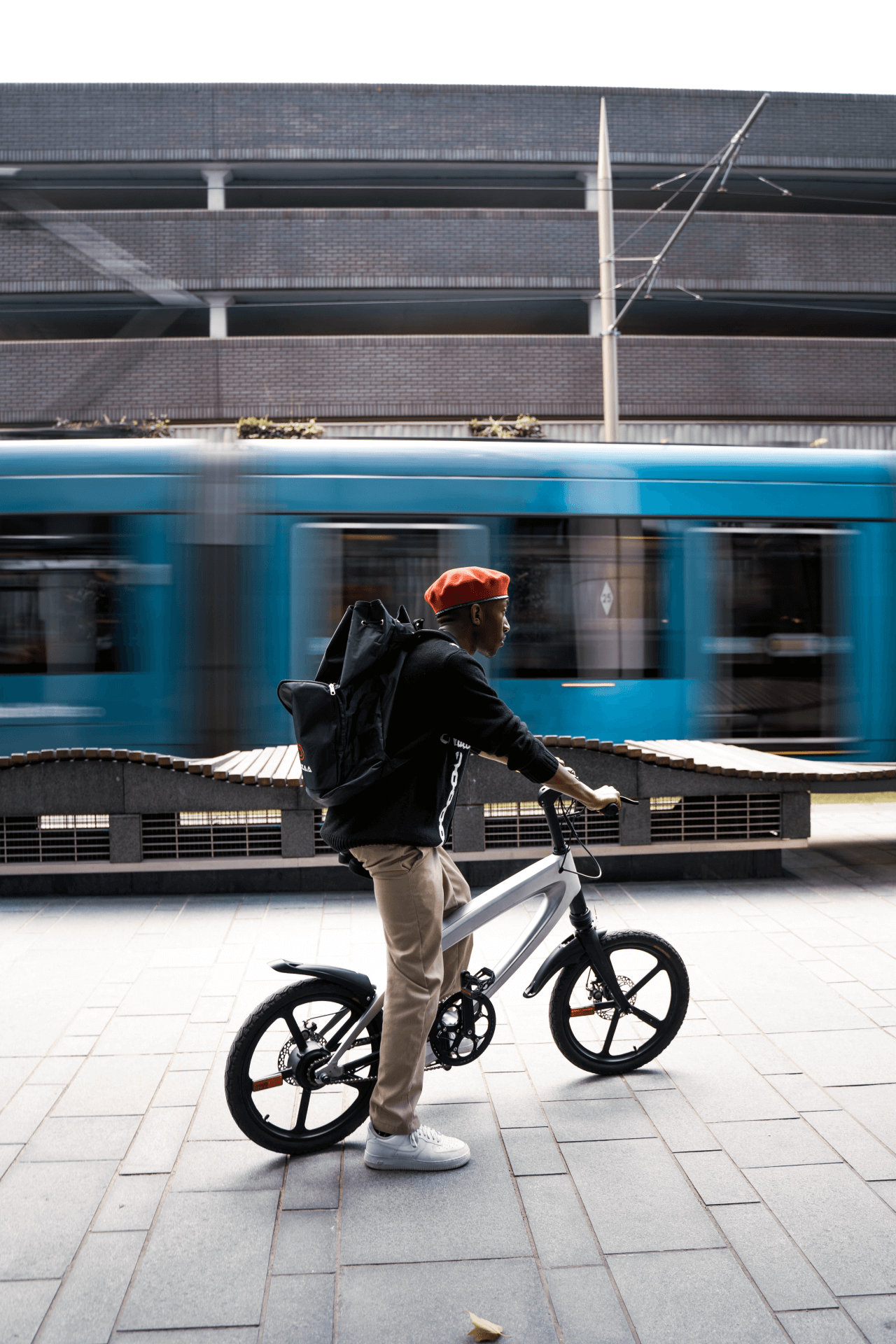 Urban cyclist on a sleek e-bike, with a blue train in motion behind, showcasing outdoor adventure and travel vibes.