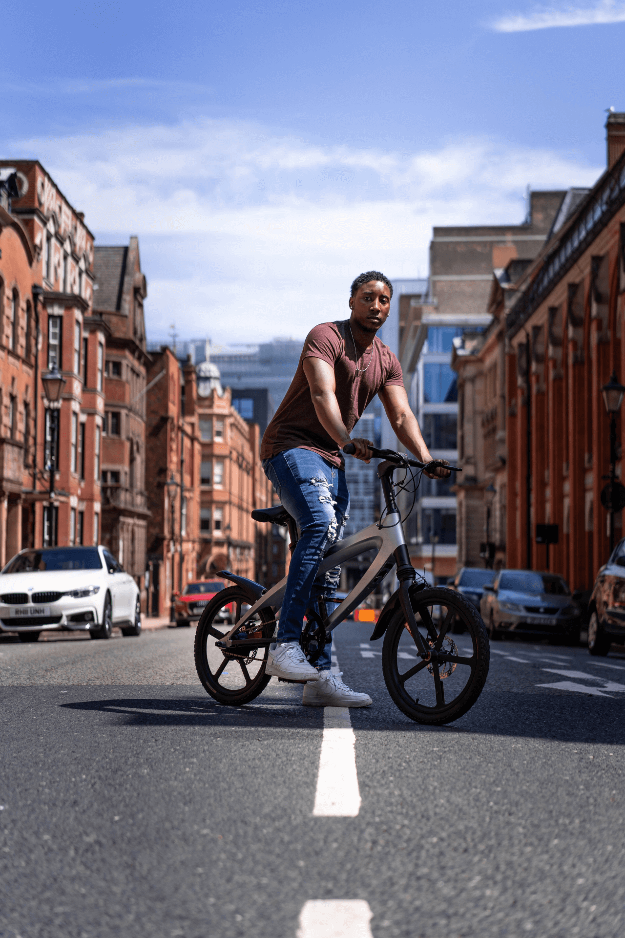 man riding a gun metal grey e-bike on an urban street, showcasing adventure and outdoor travel.