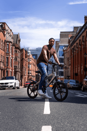 man riding a gun metal grey e-bike on an urban street, showcasing adventure and outdoor travel.