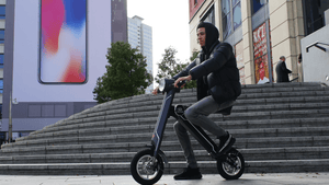 Young man riding Magno Green Cruzaa Electric Scooter in an urban outdoor setting, showcasing style and adventure.