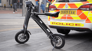 Limited Edition Cruzaa Electric Scooter parked near a police car, showcasing its stylish design for outdoor adventures.