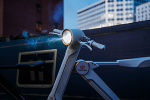 Close-up of the Cruzaa electric scooter's front light, showcasing its sleek design in an urban setting, perfect for outdoor adventures.