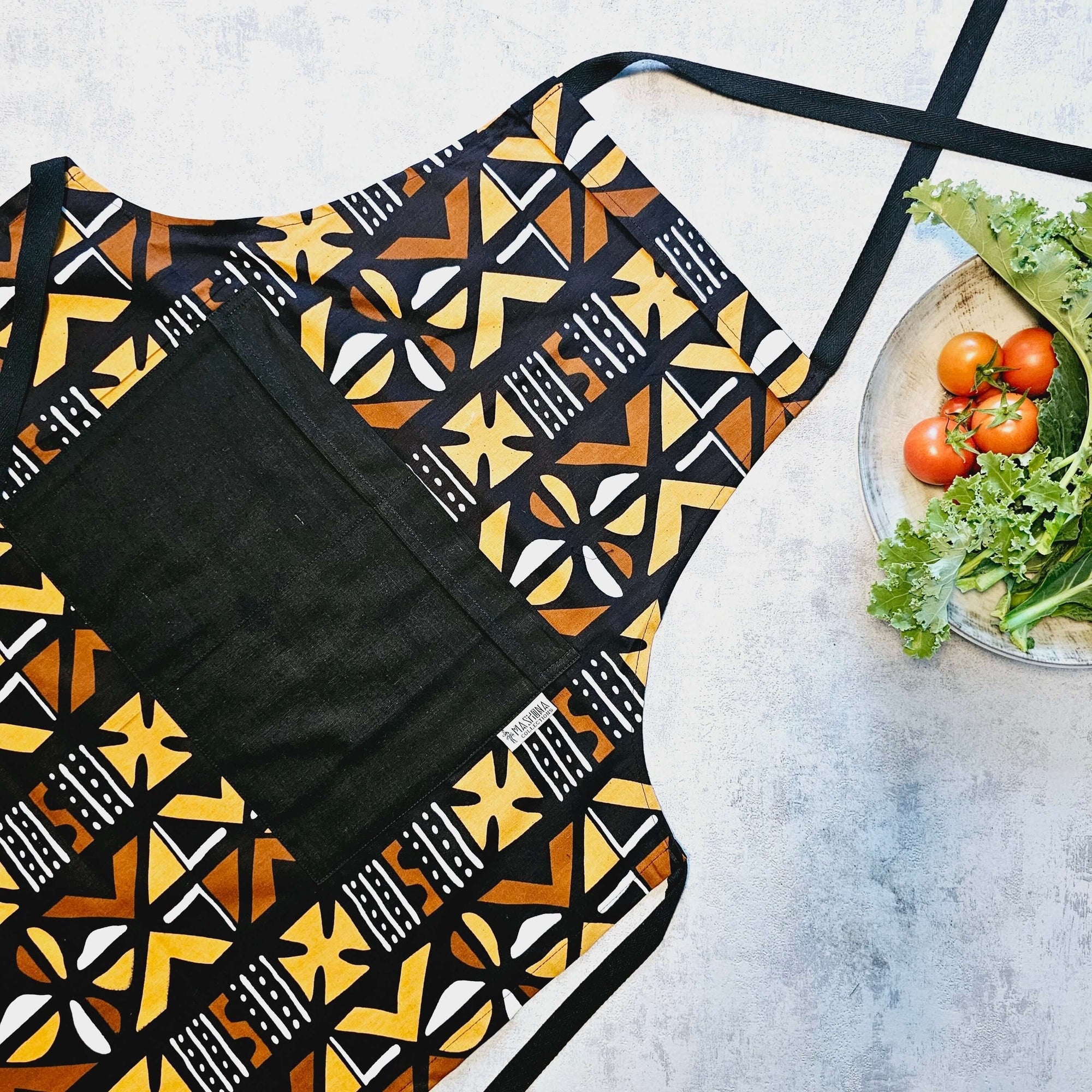 Handmade African print apron in vibrant bogolan design, perfect for outdoor cooking and adventures.