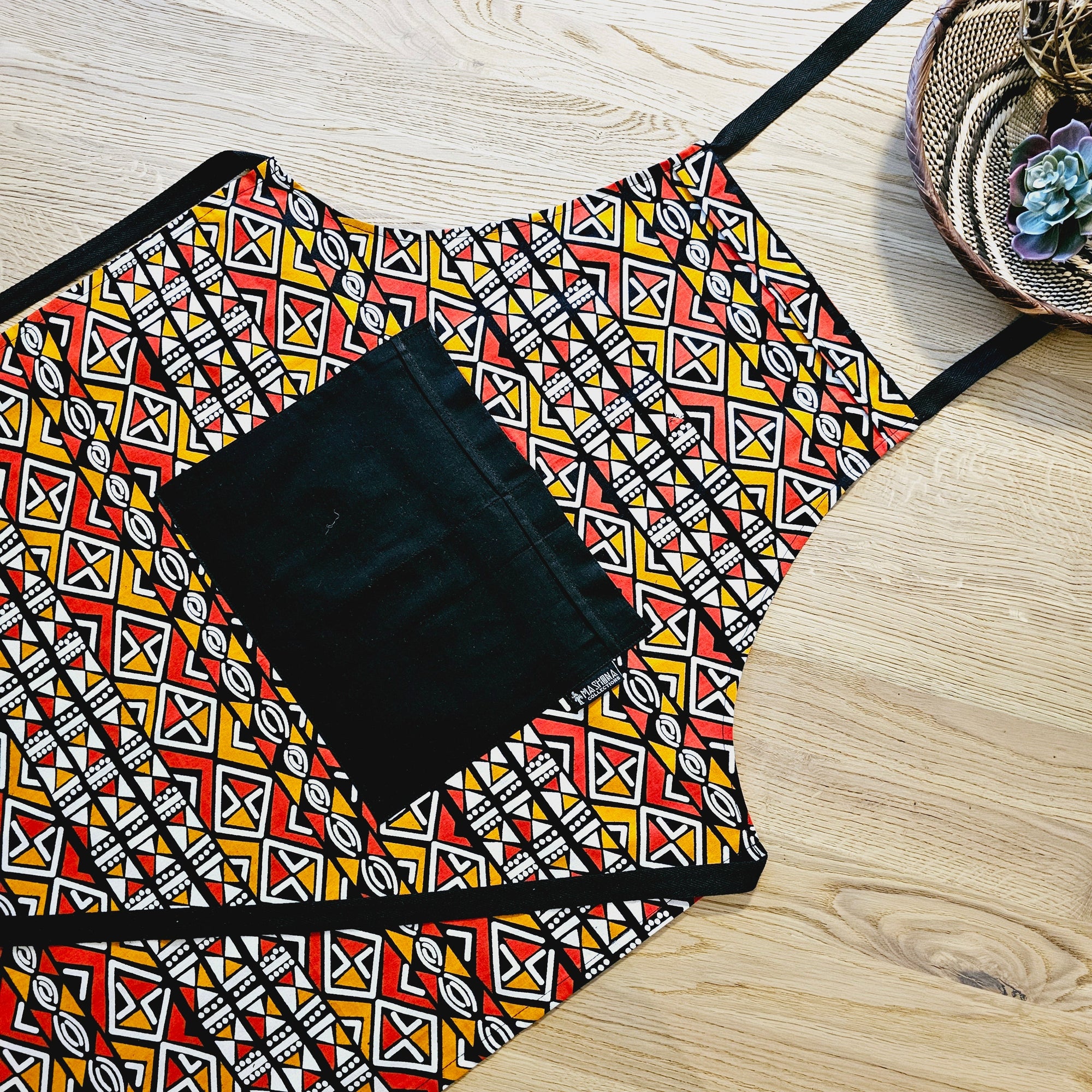 Handmade African print apron with pocket and matching oven gloves, colorful kitchen accessory for outdoor cooking adventures.