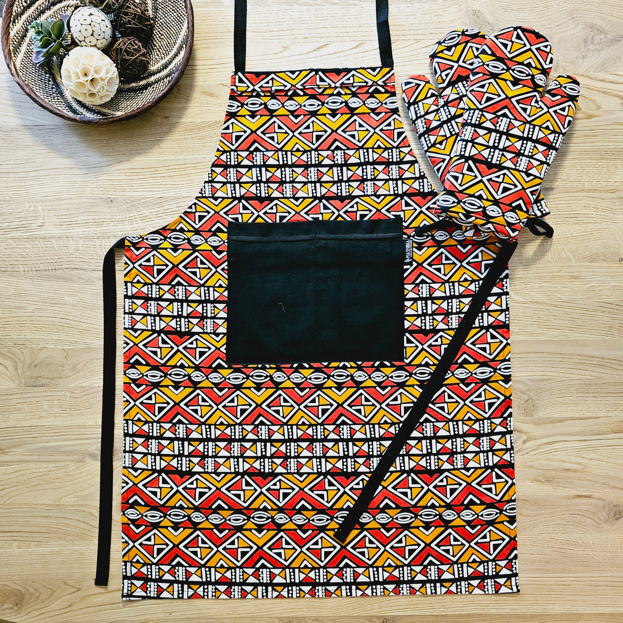 Handmade African print apron with pocket and matching oven gloves, colorful kitchen accessory for outdoor cooking adventures.