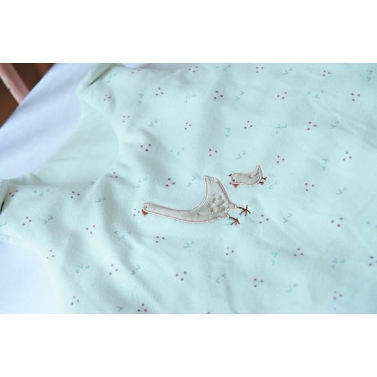 White baby sleeping bag with pink ostrich design, ideal for comfortable sleep for toddlers.