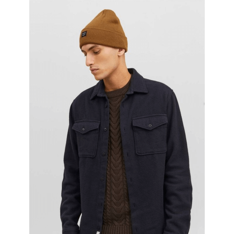 Man wearing a stylish brown beanie and dark jacket, showcasing eco-friendly winter fashion for outdoor adventures.