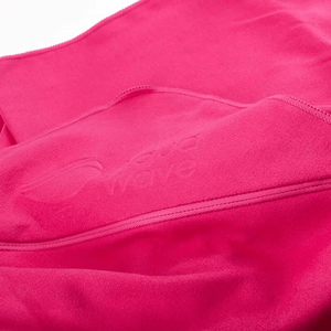 Close-up of Aquawave Playa quick-drying microfiber towel in pink, showcasing logo and fabric texture.