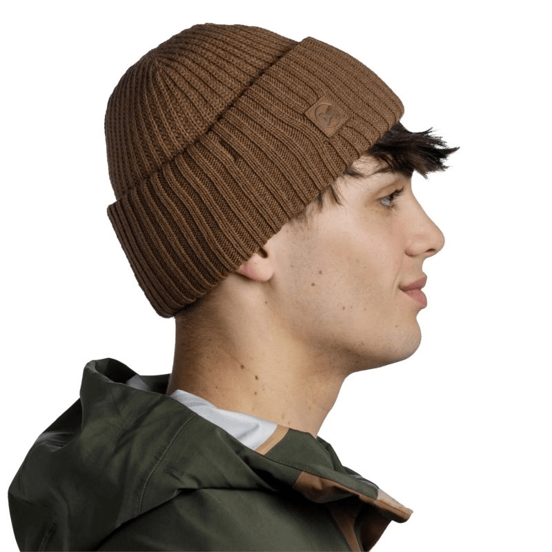 Buff Rutger Winter Beanie in brown worn by a young man, showcasing its stylish and cozy design for outdoor adventures.