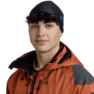 Buff Thermonet Beanie in black worn by a young man, ideal for outdoor winter sports and adventures.