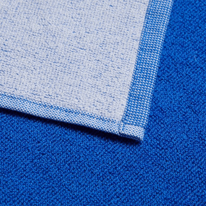 close-up of Adidas 3BAR L Towel, showcasing blue and white premium cotton texture, ideal for sports and outdoor adventures.