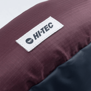 Hi-Tec logo on the waterproof fabric of a maroon and navy waist bag, showcasing durability and quality for outdoor adventures.