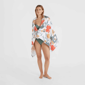 woman wearing O'Neill Mix & Match Seacoast Towel at the beach, showcasing colorful floral design, perfect for outdoor adventures.