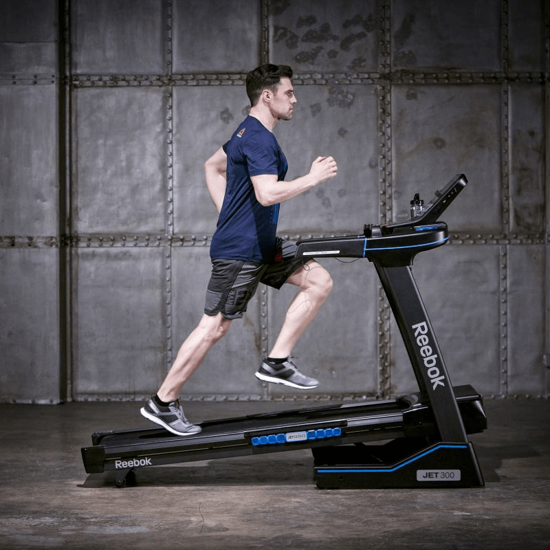 Man running on Reebok JET 300 treadmill showcasing advanced technology and robust performance for outdoor sports enthusiasts.