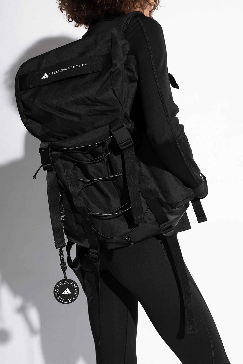 Stylish ADIDAS by Stella McCartney black outdoor backpack with adjustable straps and decorative lacing, perfect for travel and adventure.