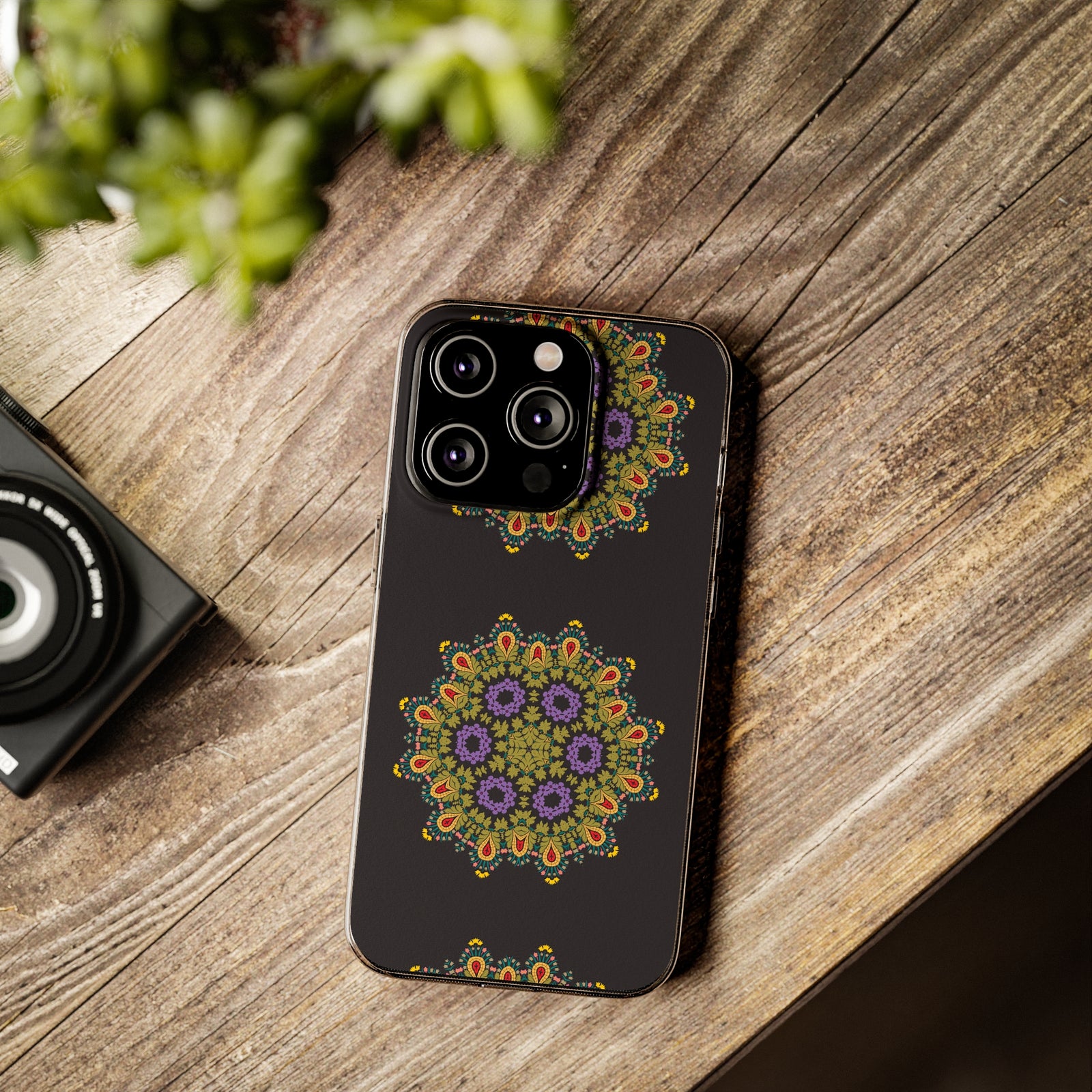 Phone case with gold mandala design on black background on a wooden surface, ideal for outdoor adventures.