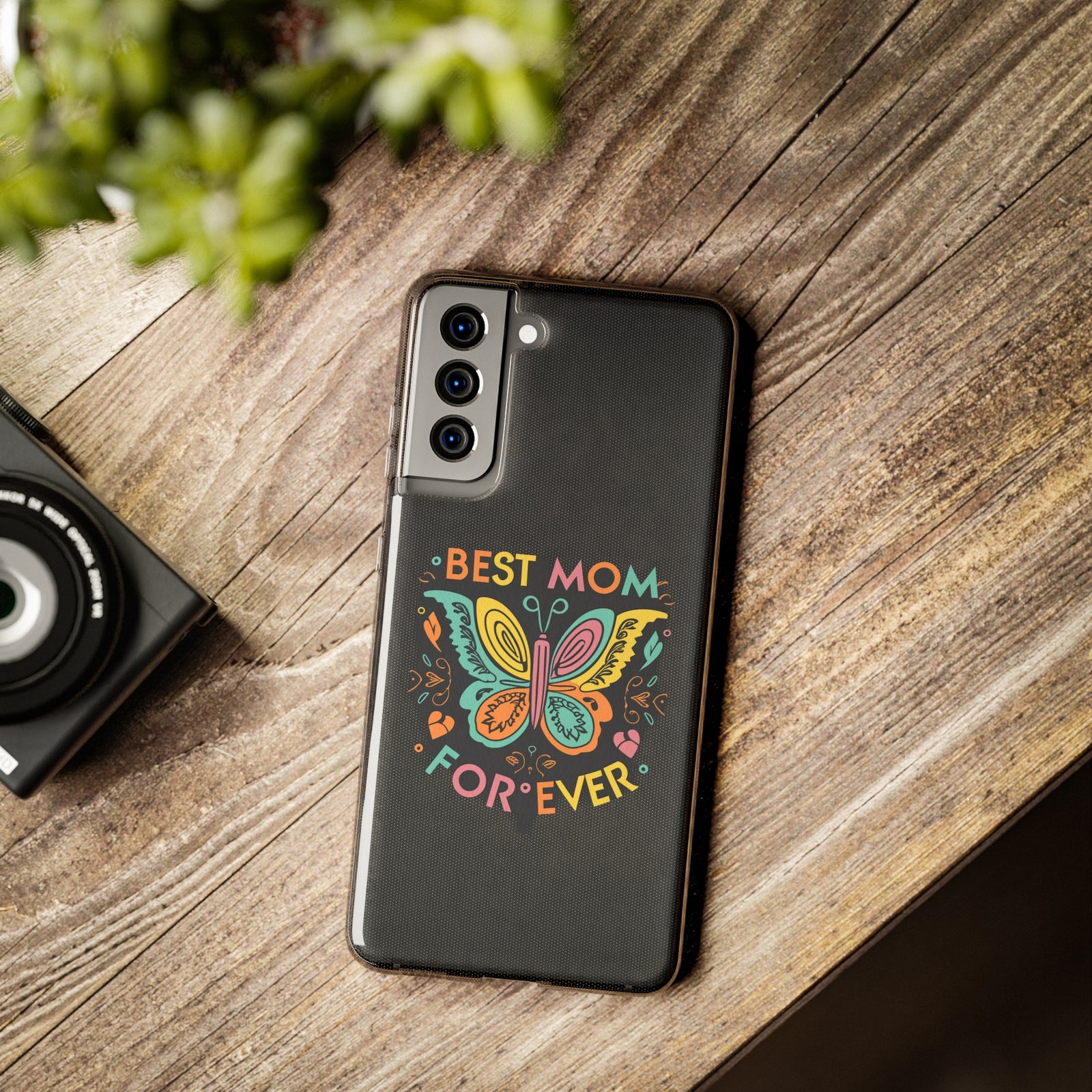 Colorful 'Best Mom Forever' phone case on wooden table, perfect for outdoor adventures and family camping trips.