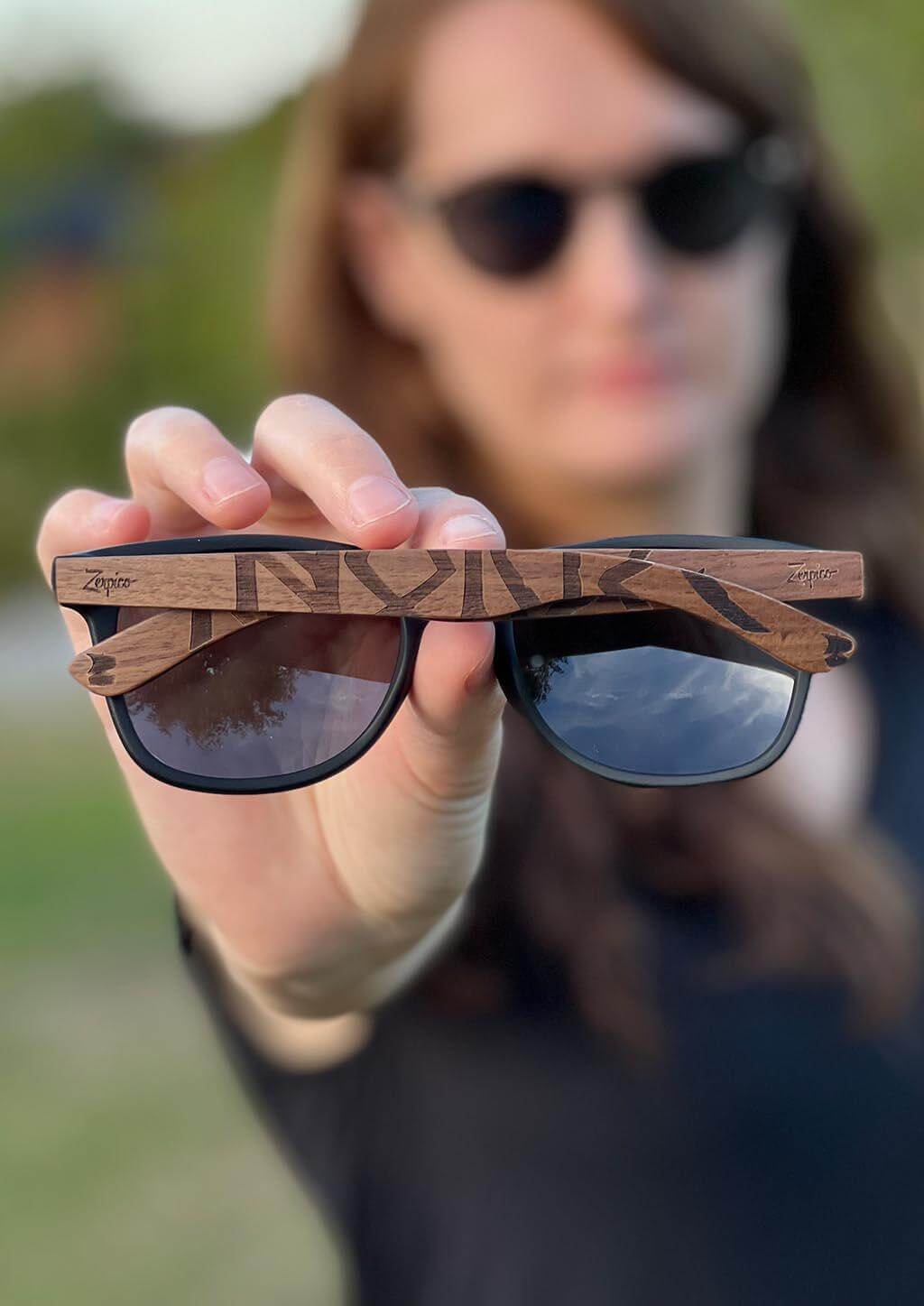 Handheld Eyewood engraved wooden sunglasses with Viking runes, perfect for outdoor adventures and camping.