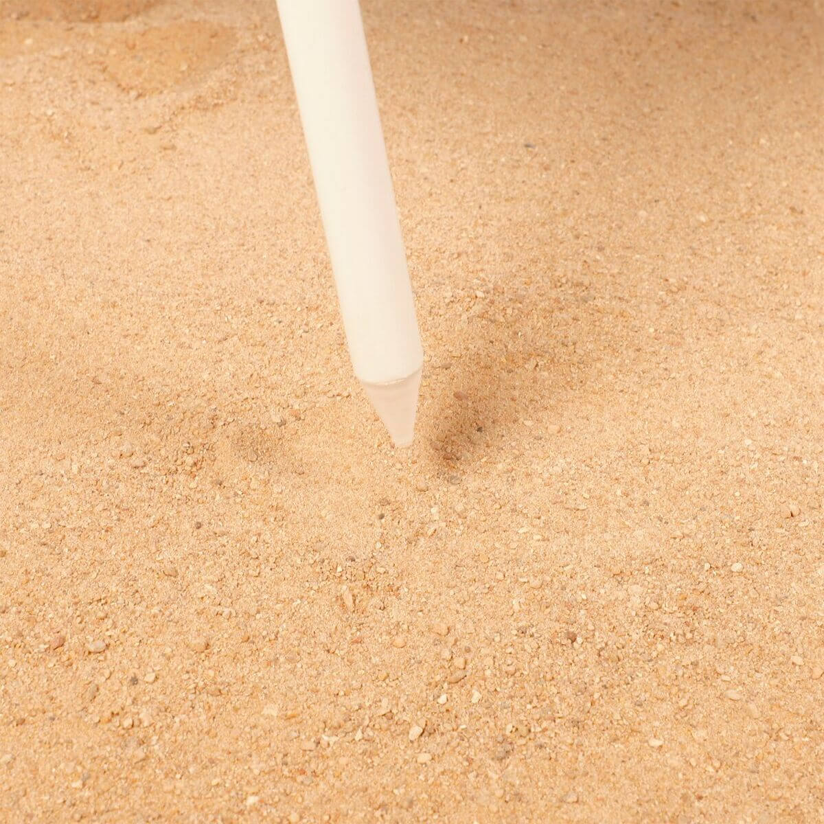 Beach tent peg being inserted into sandy ground for outdoor camping adventures at revlando.com.